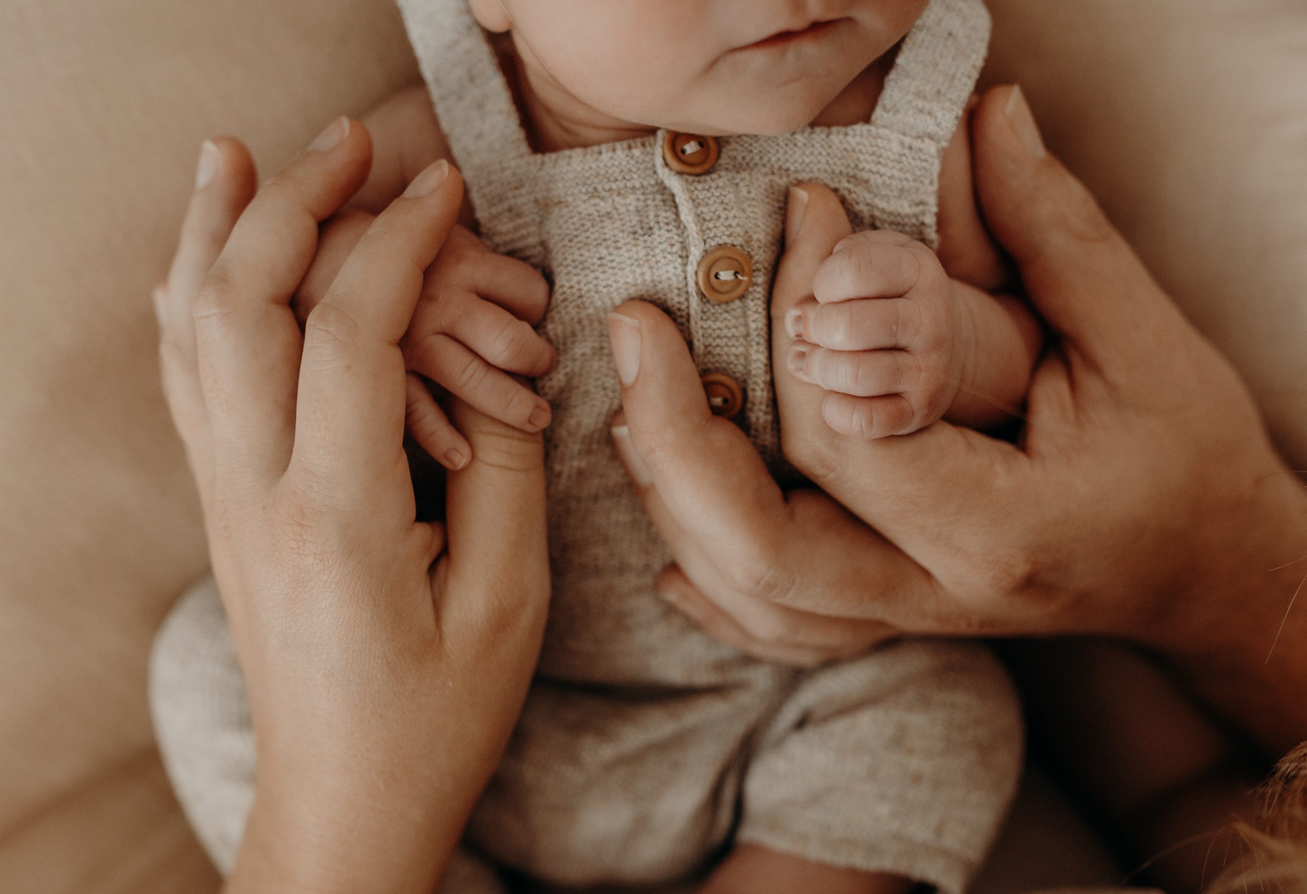 Babyfoto von Baby was sich mit Händchen an den Händen von Mama und Papa fest hält in Königstein im Taunus