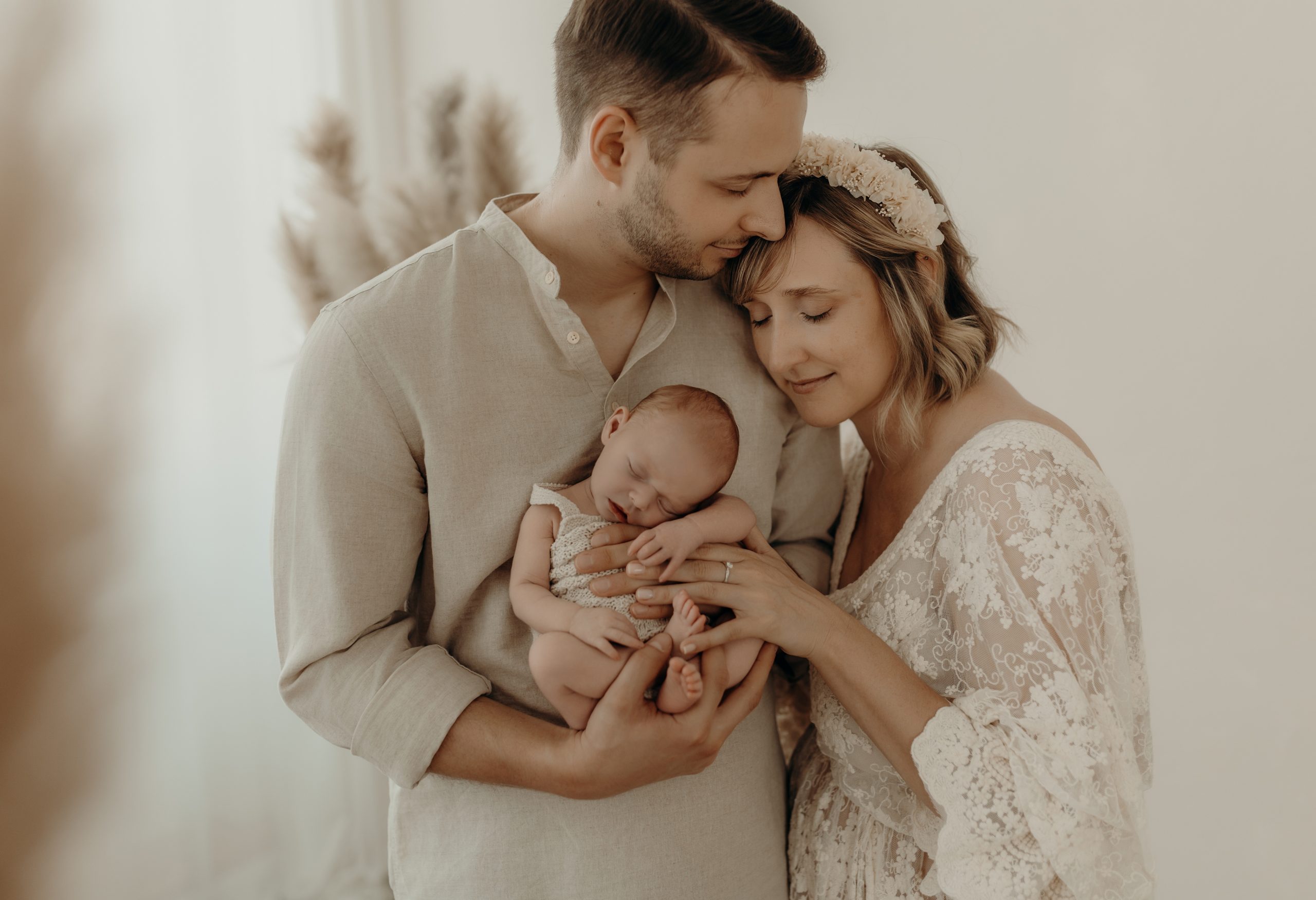 Familie mit Mama Papa und Baby kuscheln sich zusammen mit geschlossenen Augen