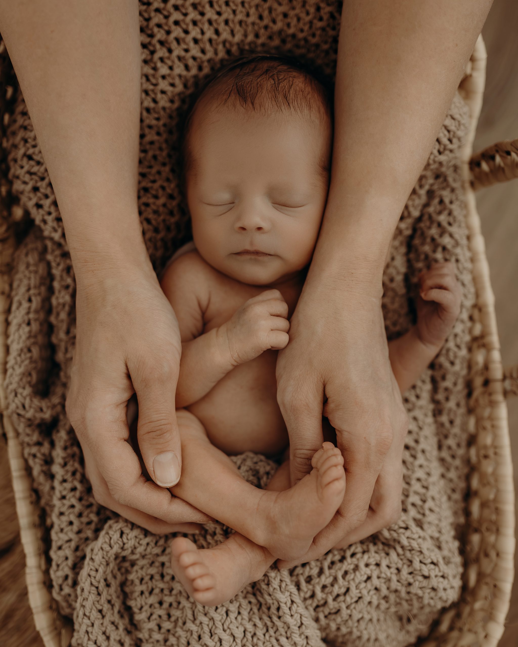 Baby schläft in den Händen der Mama im Körbchen bei Babyfotograf Daniela Herold Fotografie