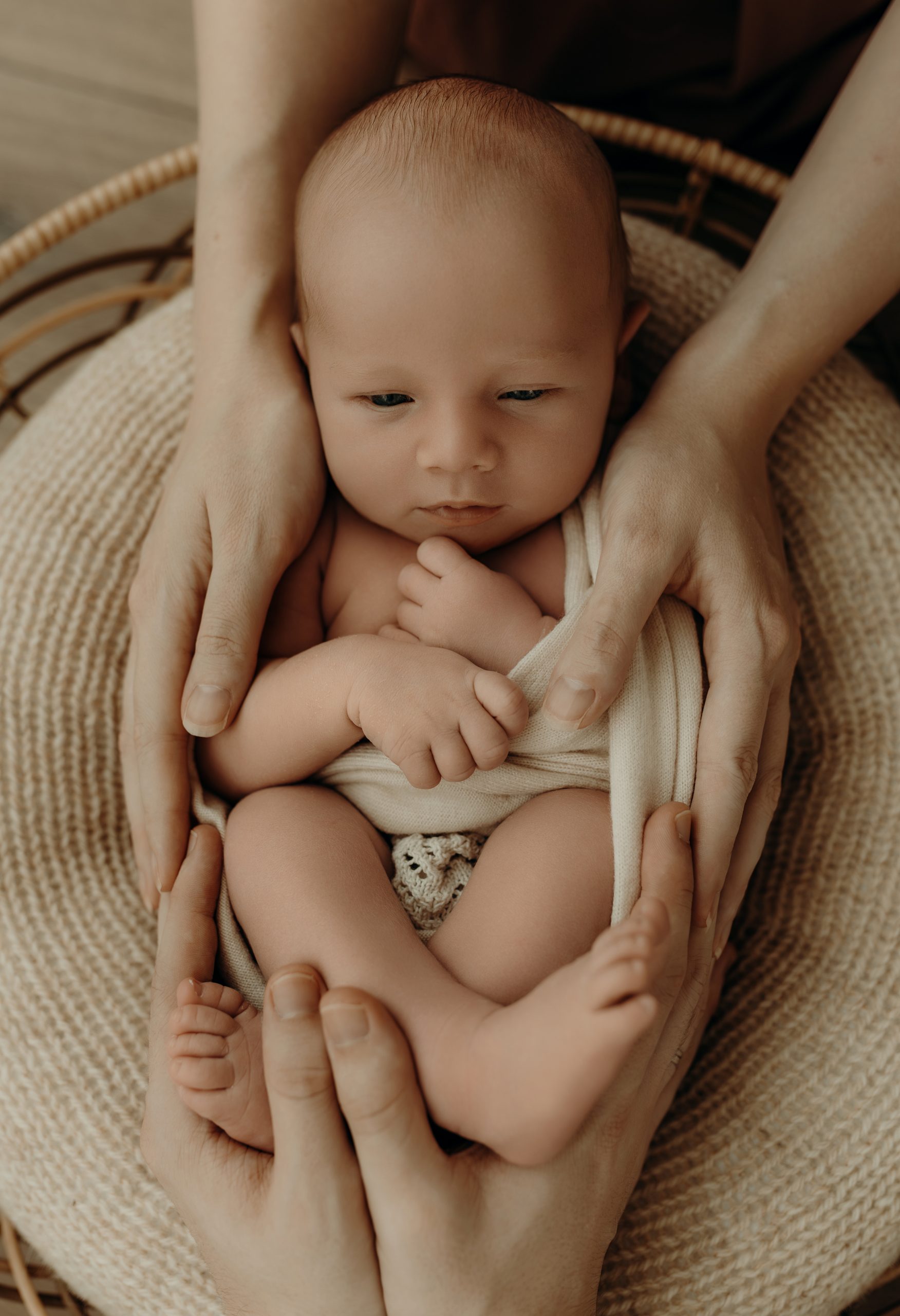Neugeborenes Baby im Körbchen mit den Eltern von Mama und Papa an ihm