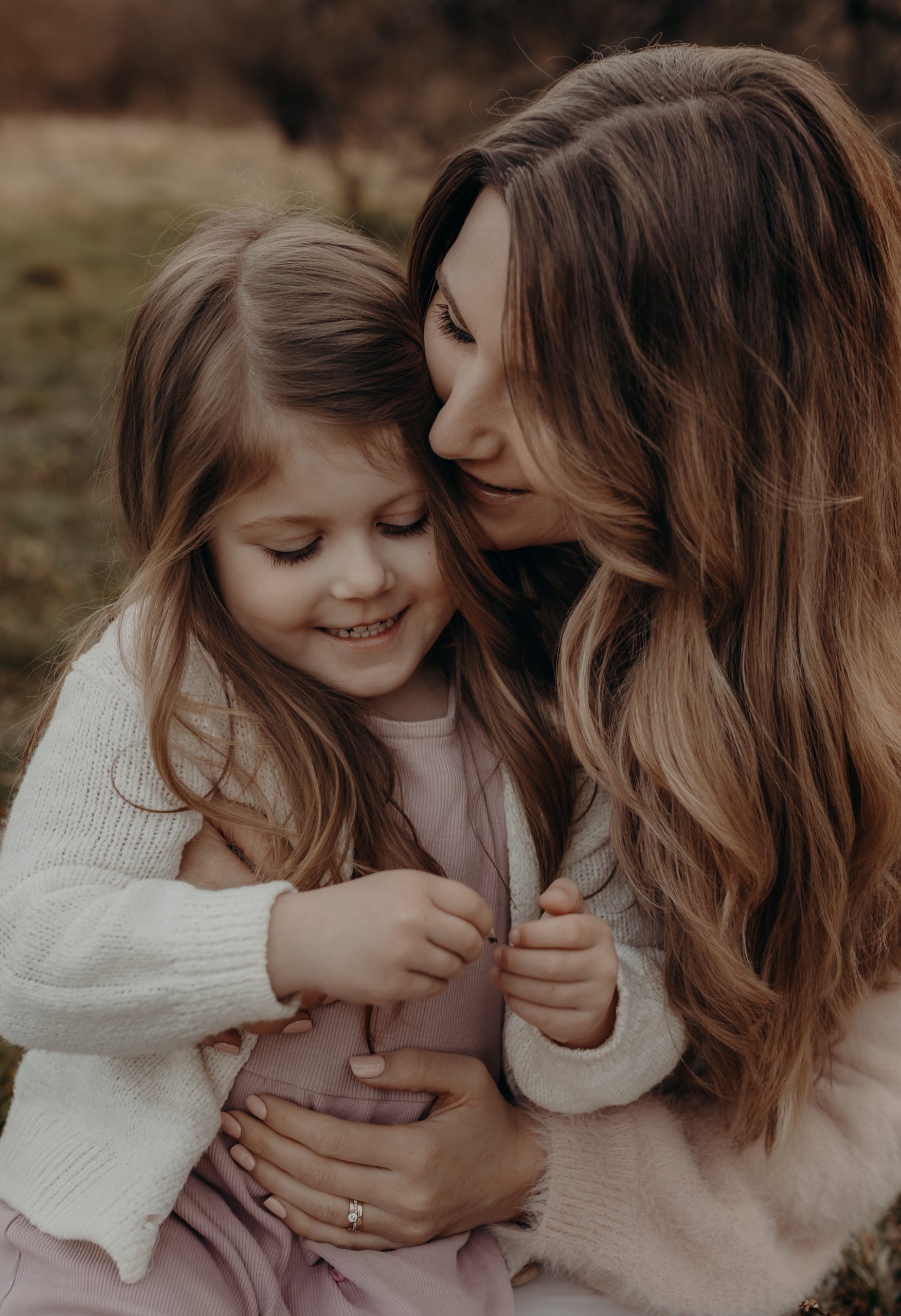 Mama kuschelt sich ganz eng an kleine Tochter beim Outdoor Familienshooting in Hanau