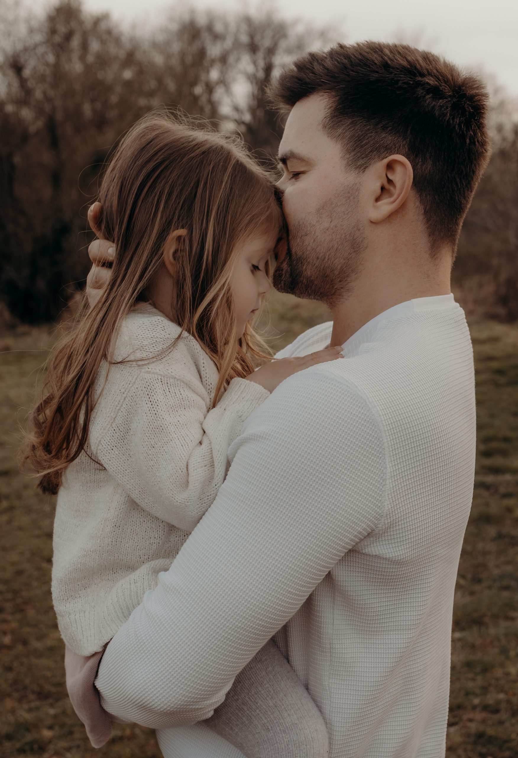Papa hält kleine Tochter auf dem Arm, drückt sie an sich und gibt ihr einen Kuss auf die Stirn beim Fotoshooting in Frankfurt